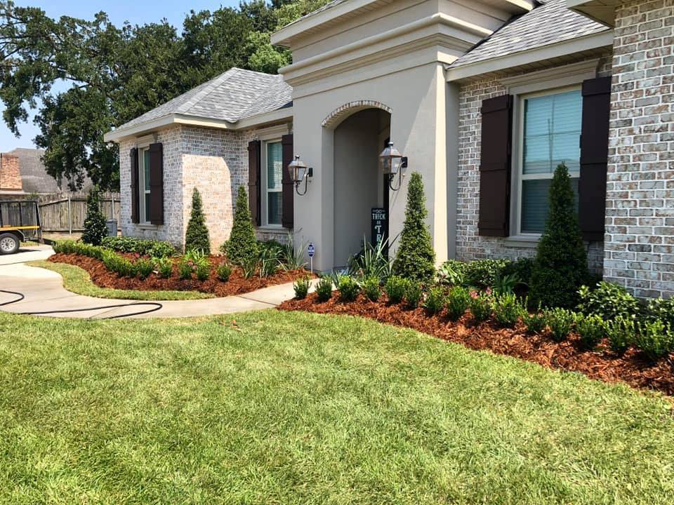 Manicured front lawn with a beautifully curated flower bed, complete with vibrant greenery and mulch, showcasing the landscaping expertise of Southern Grounds LLC in Marrero, LA.