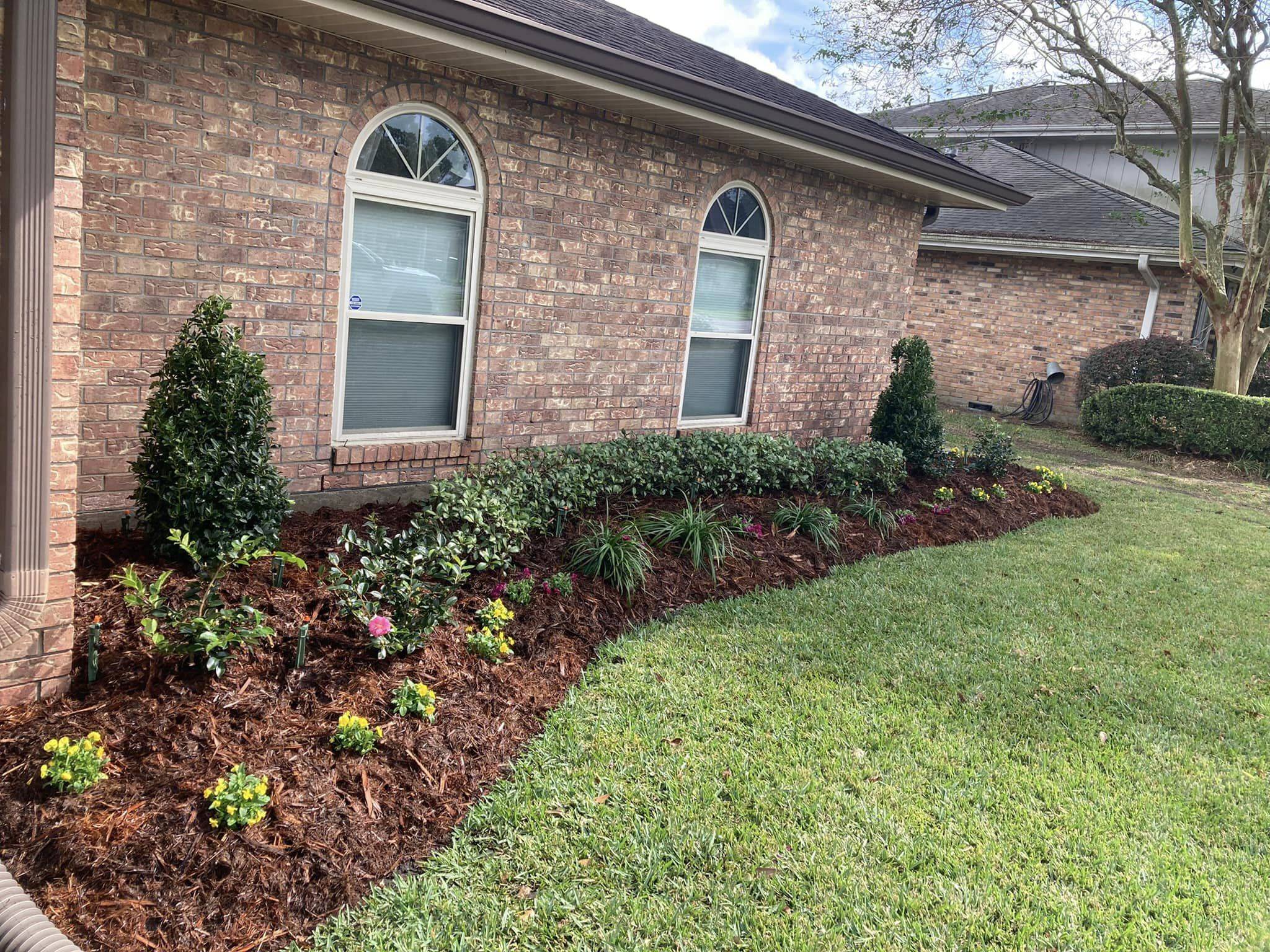 Elegant residential landscape featuring a fresh mulch garden bed with blooming flowers and shrubs, carefully tended by Southern Grounds LLC in Marrero, LA.
